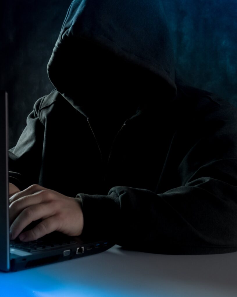 person in a hood hacking into a website